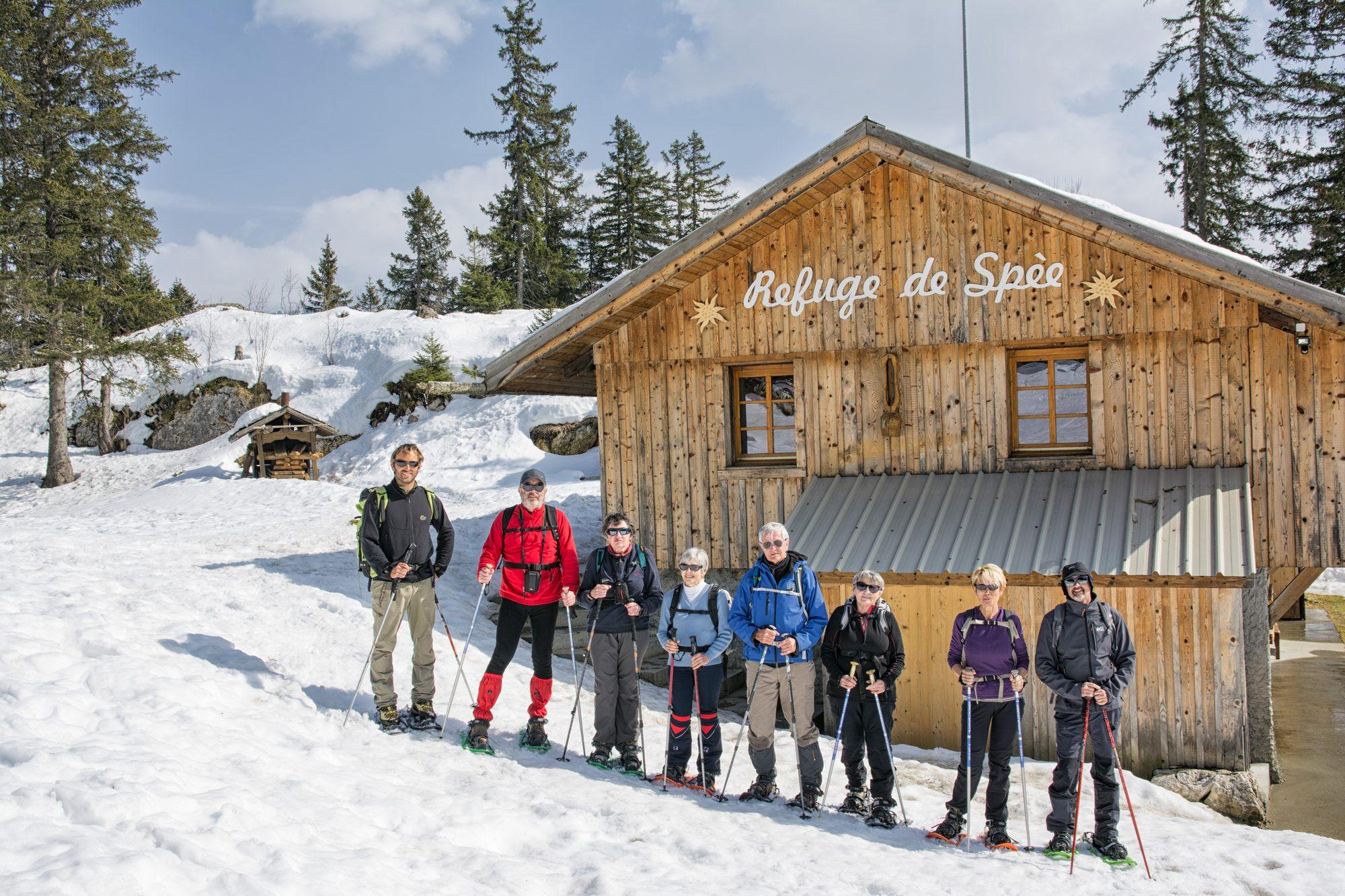Groupe en raquettes devant un refuge de montagne