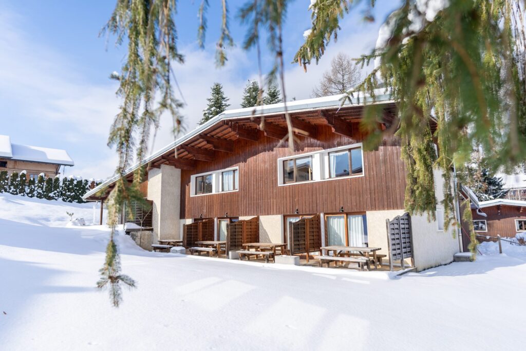 Chalet traditionnel sous la neige entre les sapins