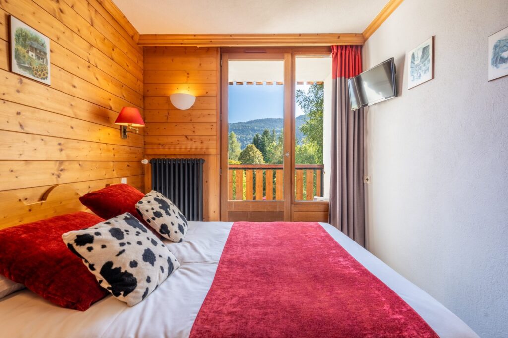 Chambre avec accès balcon et literie rouge