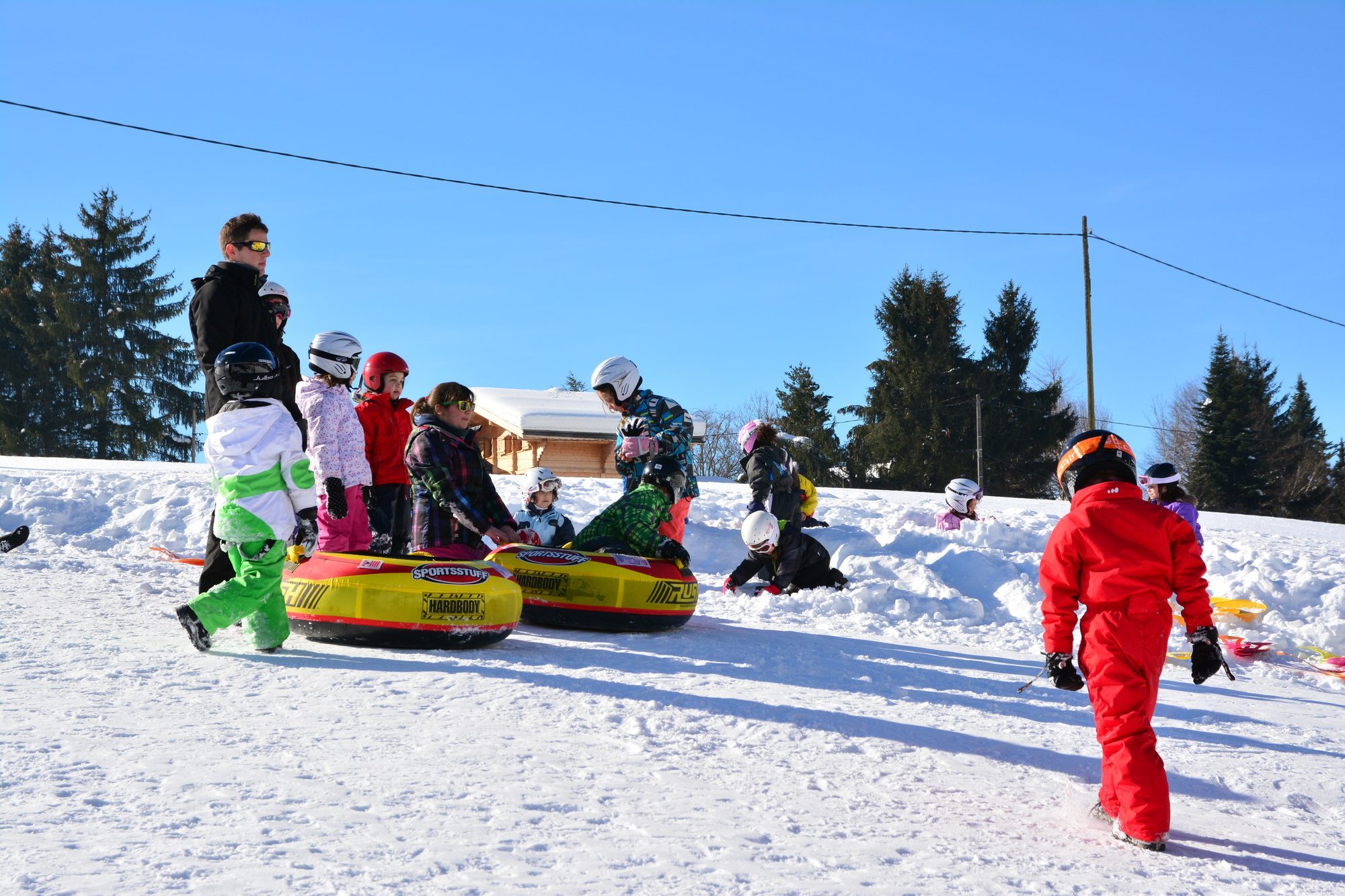 Enfants tractés sur bouées de neige entre les sapins