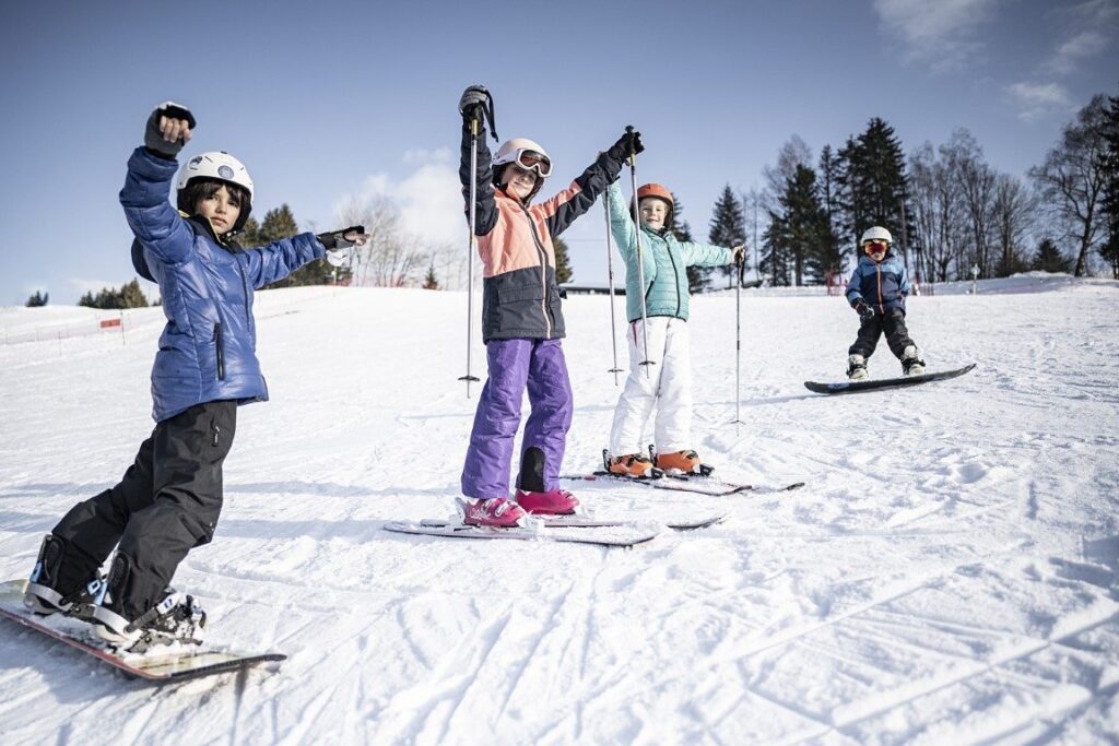 Groupe d'enfants skieurs bras levés