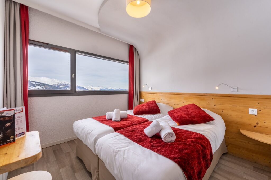 Chambre avec fenêtre ronde et literie rouge