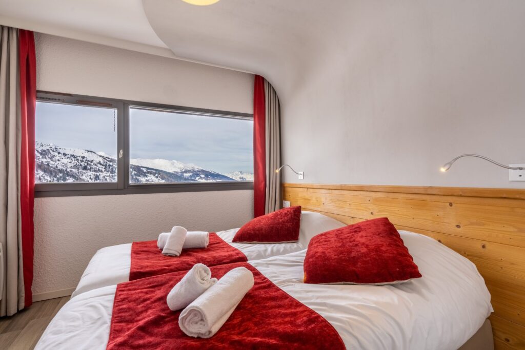 Chambre avec vue sur la montagne et literie rouge