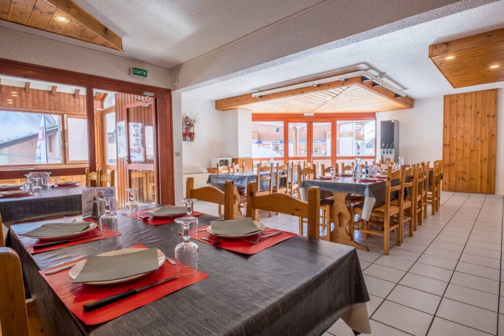 Salle de restaurant aux tables dressées en longueur