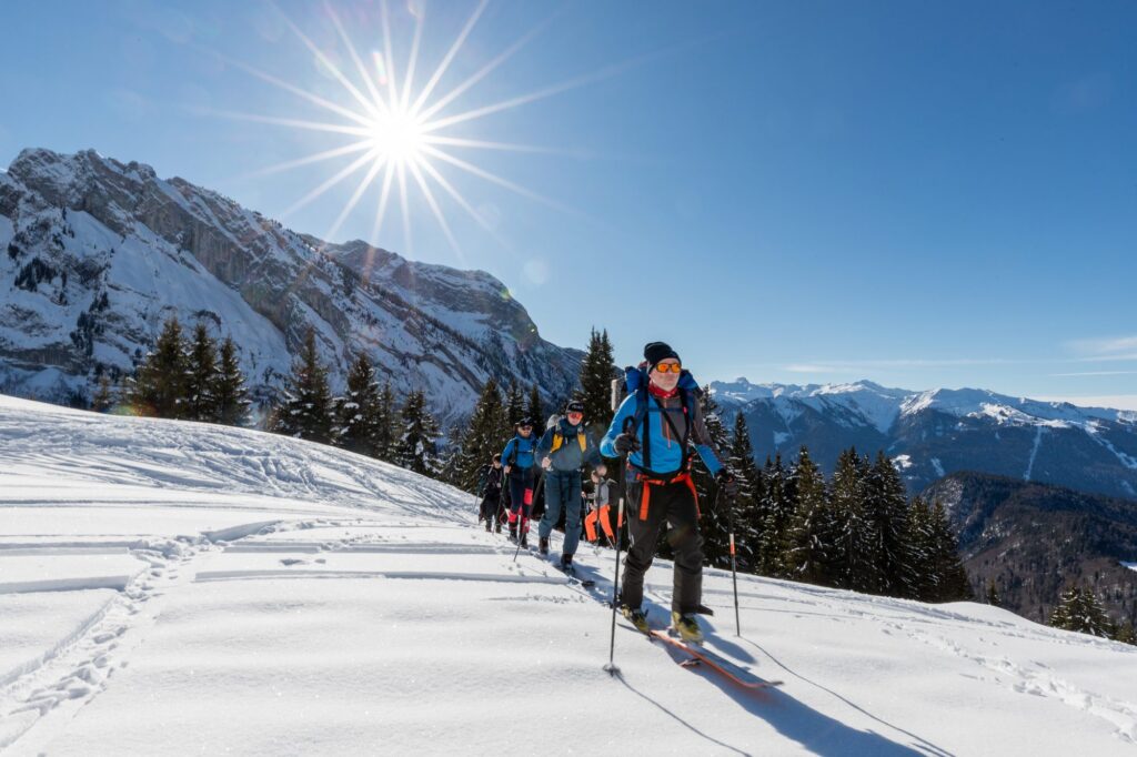 Skieur de randonnée face au soleil en montagne