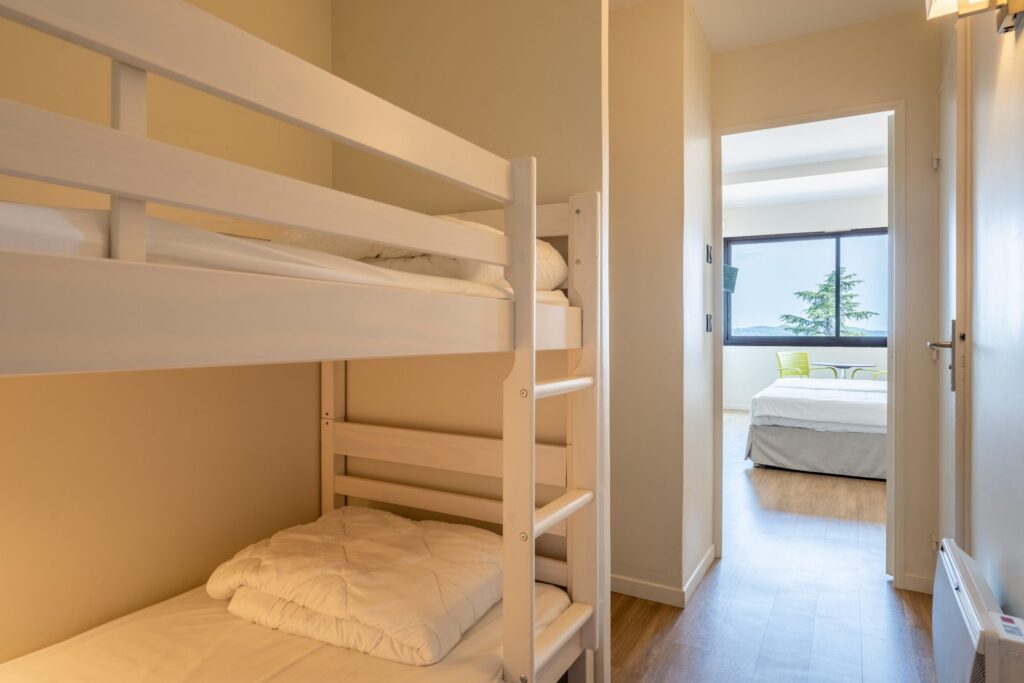 Chambre avec lits superposés et vue lointaine sur la mer