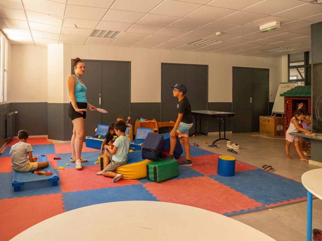 Animateurs jouant avec des enfants sur des tapis colorés
