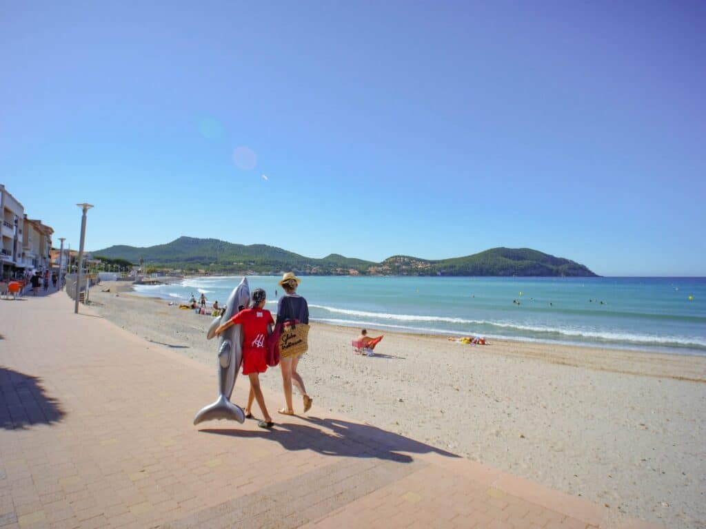 Couple marchant sur une passerelle de plage avec un paddle