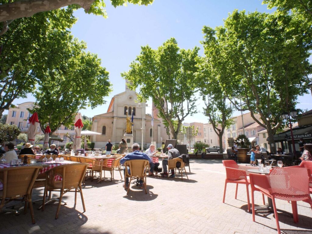 Place de village animée avec terrasse de café