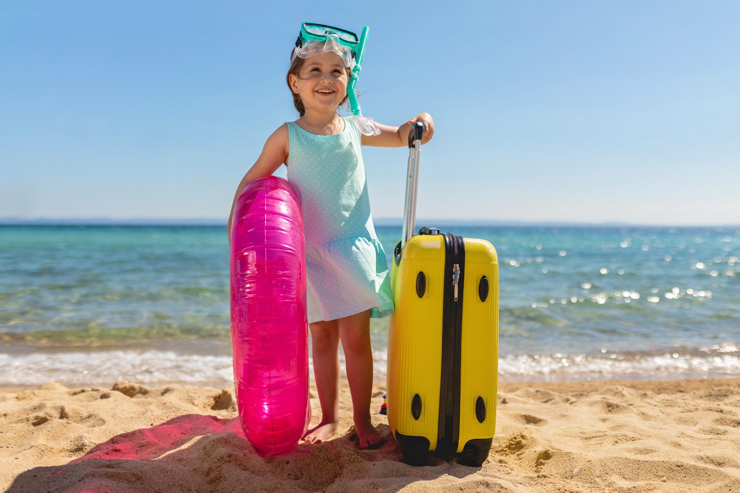 Enfant avec bouée et valise sur la plage